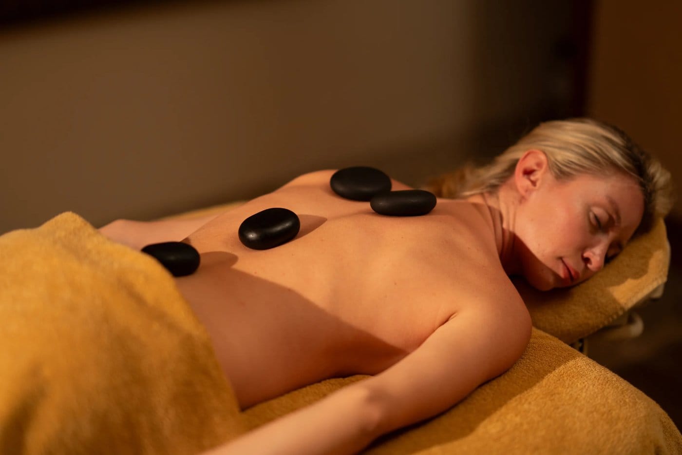 Guest unwinding during a hot stone massage session in a warm, calming spa room