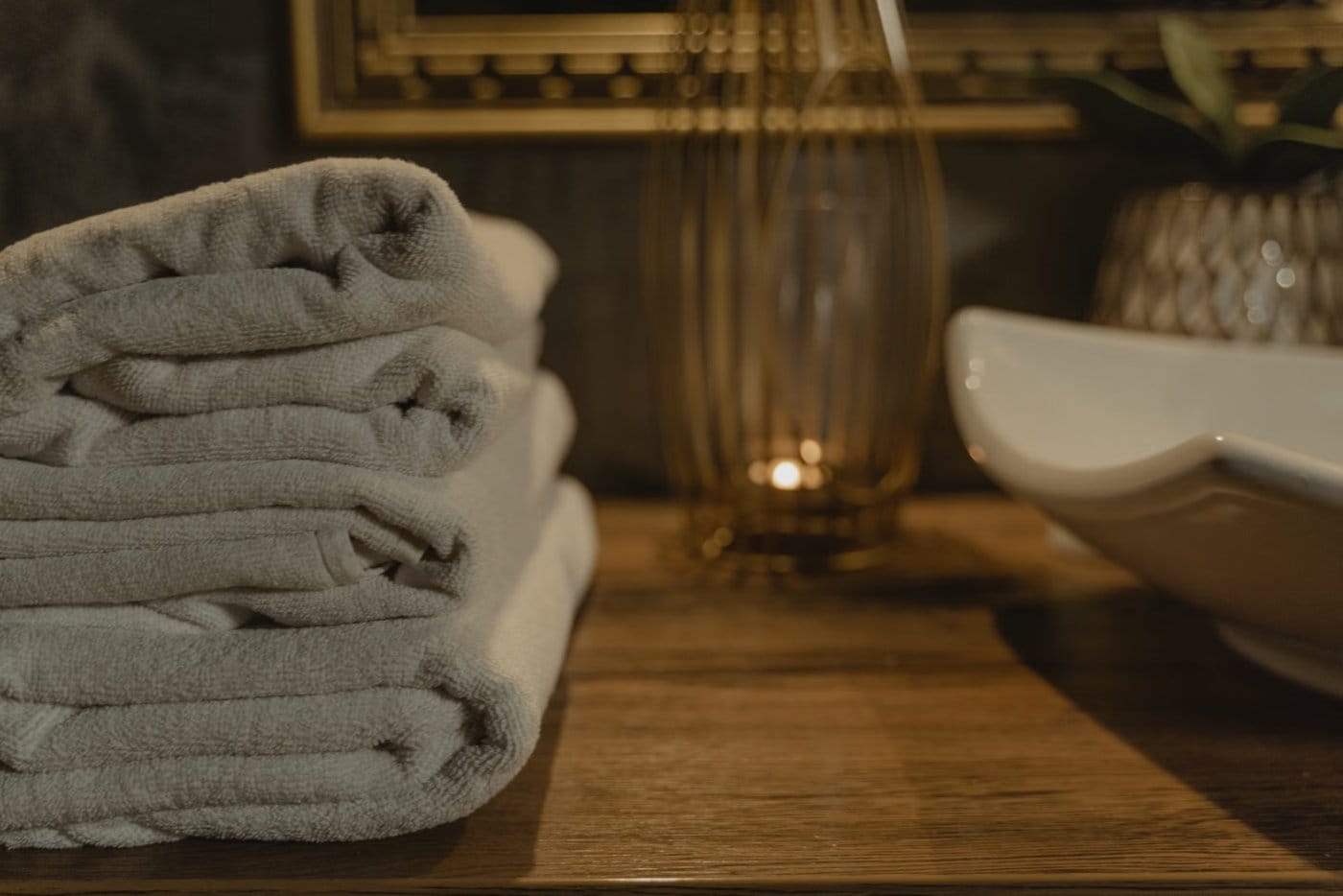 Soft stacked white spa towels in warm candlelight at Flamingo House Spa